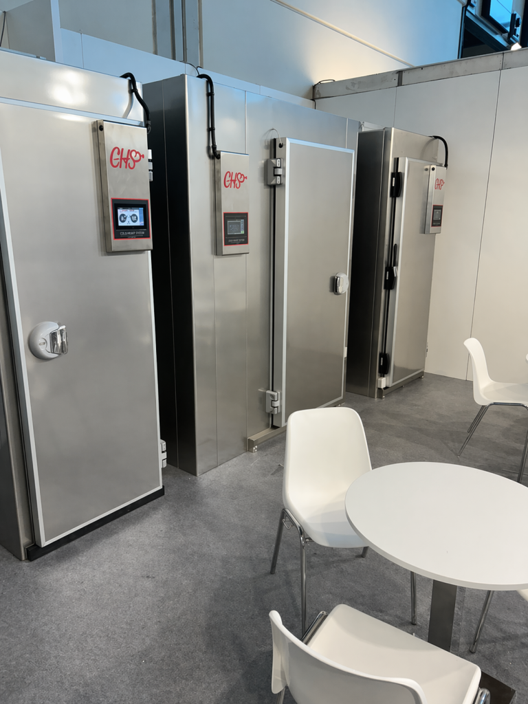 Celle frigorifere CHS in acciaio inox con controllore frontale installate in ambiente showroom con tavolo e sedie.